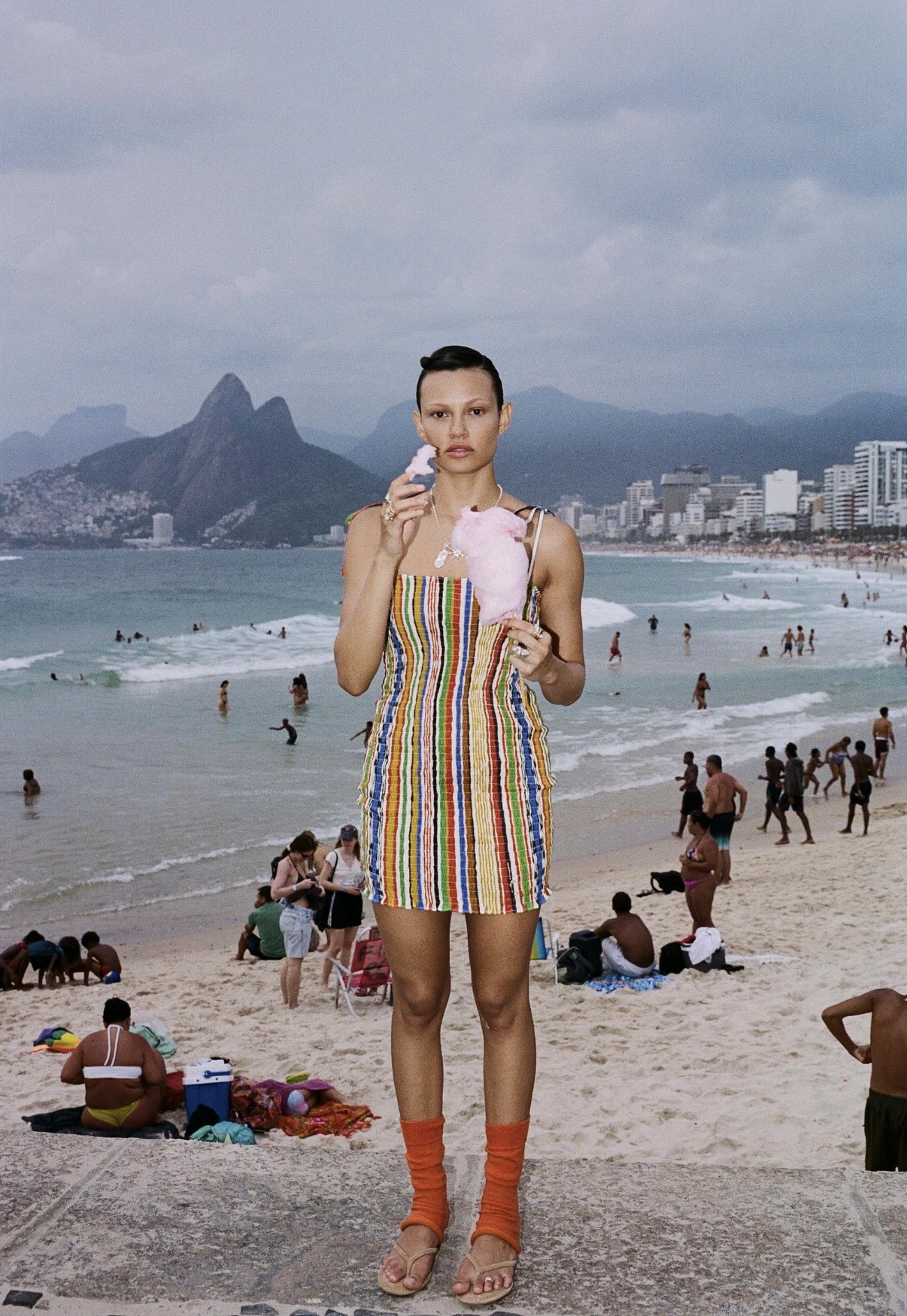 Model in a striped dress eating cotton candy on the stone steps at Ipanema Beach, Rio de Janeiro
